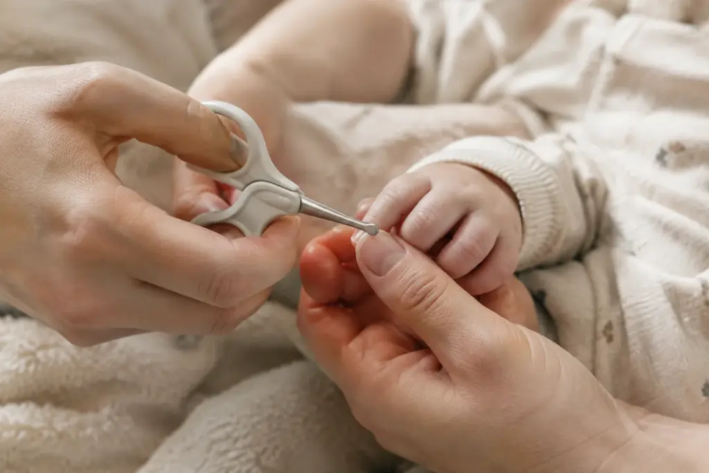 Un parent coupe délicatement les ongles d’un bébé avec des ciseaux adaptés.