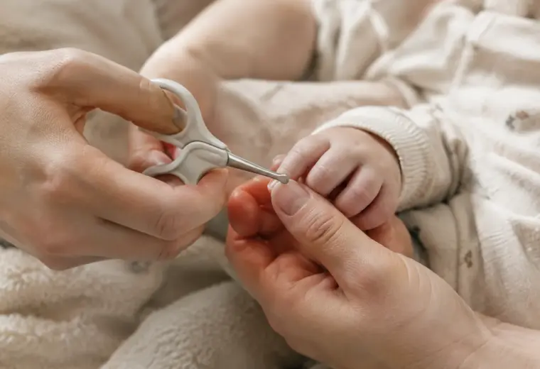 Un parent coupe délicatement les ongles d’un bébé avec des ciseaux adaptés.