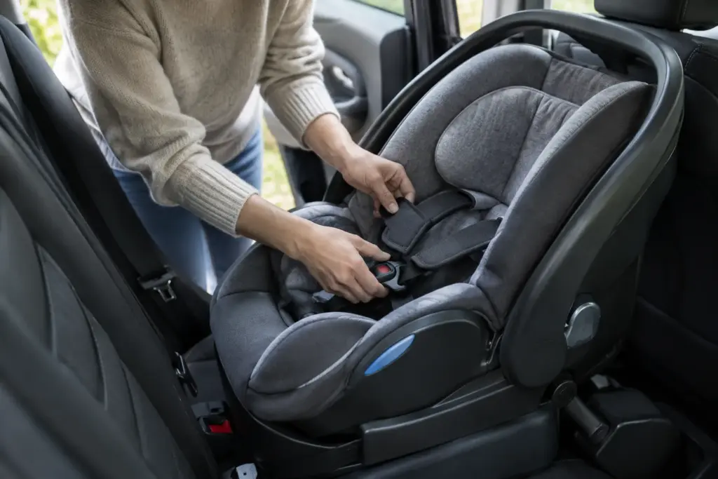 Un parent vérifie les sangles d’un siège-auto installé dos à la route sur la banquette arrière.