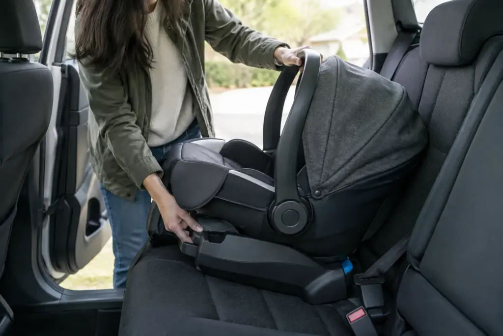 Un parent vérifie l’installation d’un siège-auto pour bébé sur la banquette arrière.