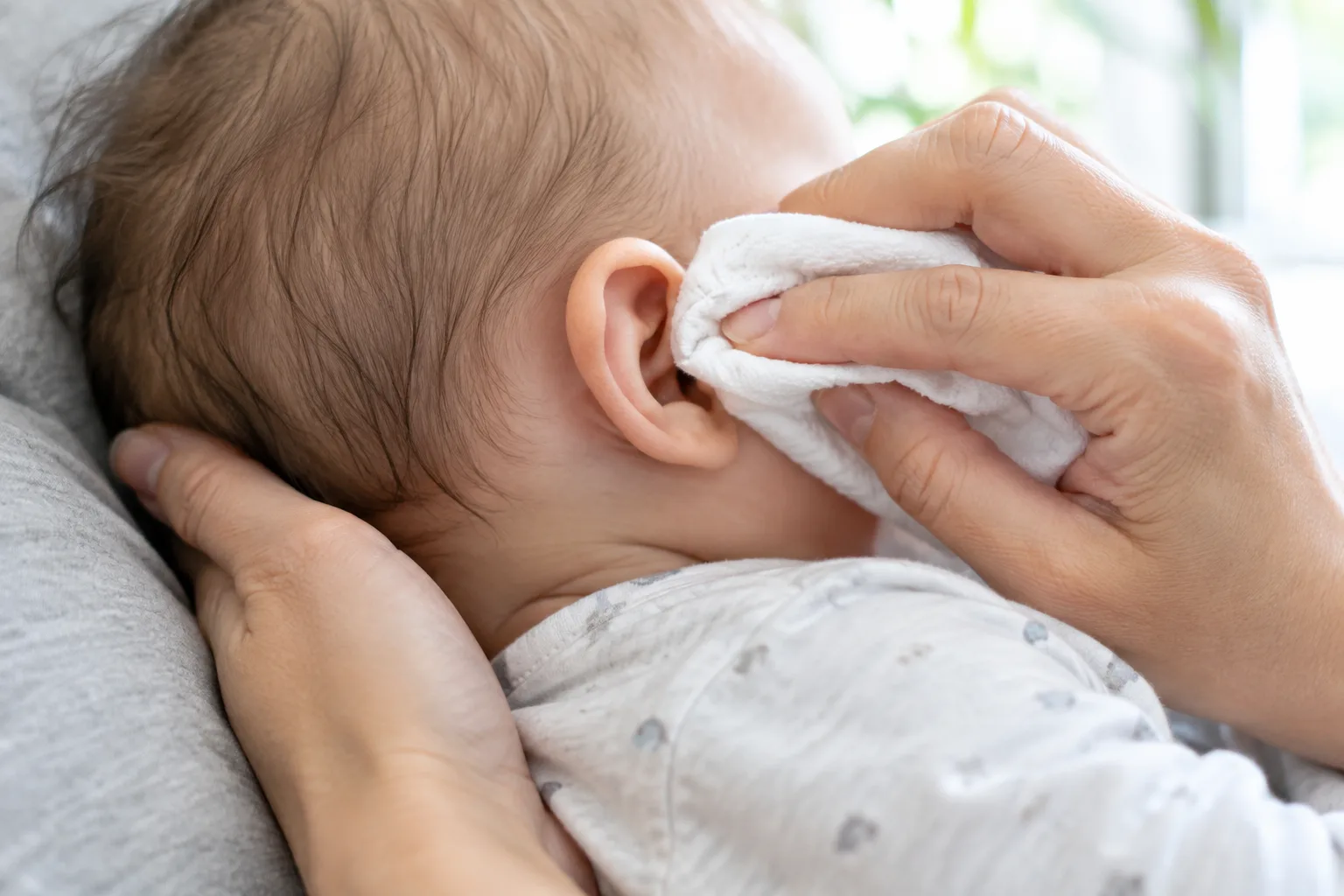 Un linge doux passe délicatement sur le pavillon de l’oreille d’un bébé.