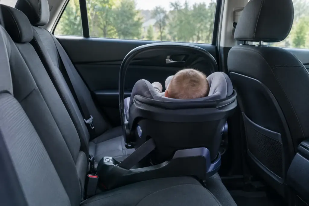 Un bébé installé dos à la route dans son siège-auto, sur la banquette arrière.