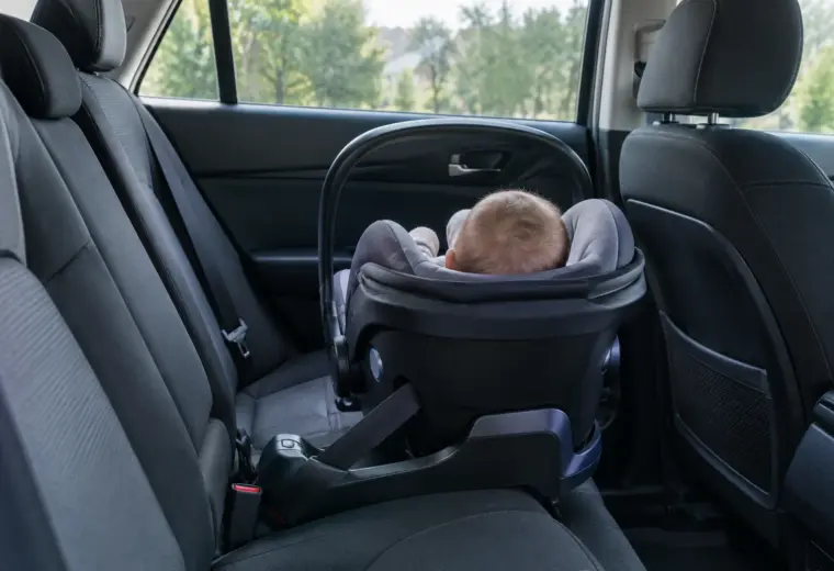 Un bébé installé dos à la route dans son siège-auto, sur la banquette arrière.